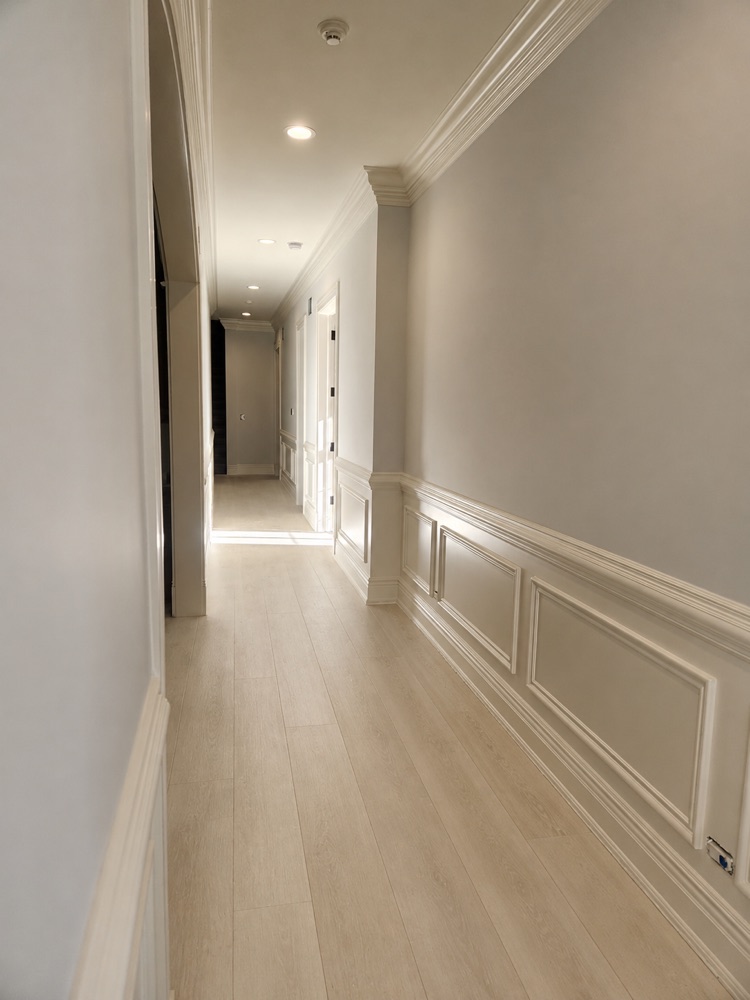 Hallway with painted wainscoting and light wood floor